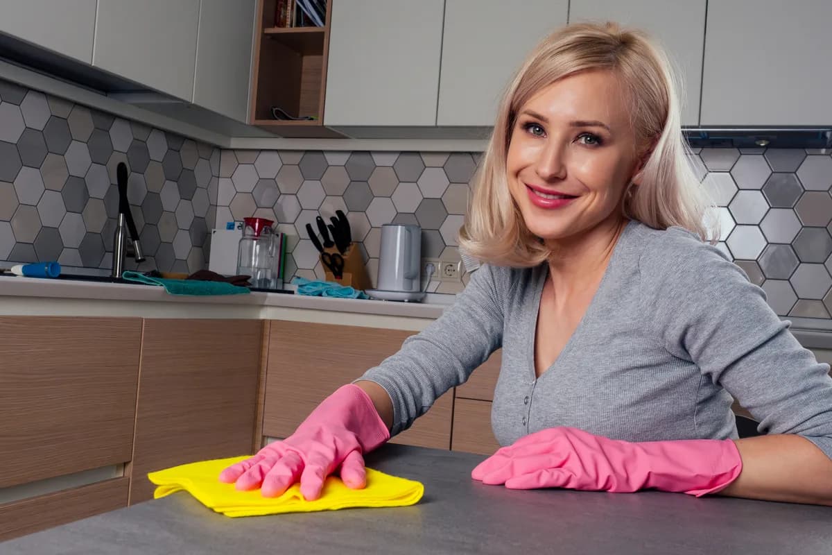 Cleaner wiping a bright kitchen counter with a cloth