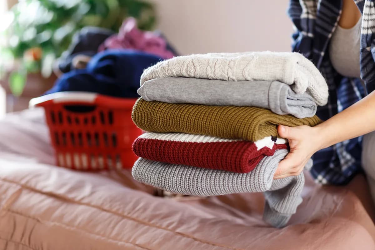 Housekeeper folding fresh laundry on a bed